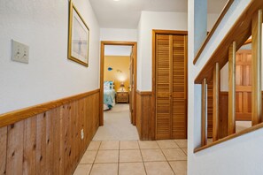 A hallway with wooden paneling, a tiled floor, a framed picture on the wall, and a door with wooden shutters. - A Dream Come True -- Pet Friendly Home with Hot Tub and Community Amenities (Duck)