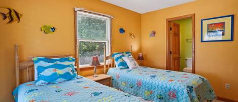 A bedroom with two beds, a window with blinds, a ceiling fan, and a painting on the wall.