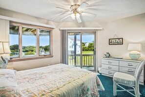 A bedroom with a large bed, a ceiling fan, a dresser, a chair, and a view of the outdoors through a sliding glass door. - Crystal Sands -- Unique 5 BR in Southern Duck with Community Amenities (Duck)
