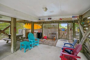 A covered outdoor seating area with wooden furniture and a pool table.