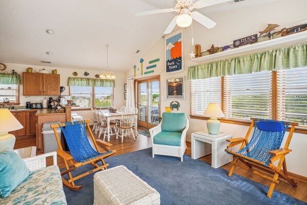 A cozy living room with wicker furniture, a dining area, and a kitchen.