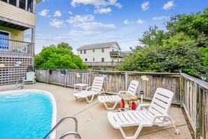 A backyard with a swimming pool, lounge chairs, and a wooden fence. - Duck Views-- 4BR Oceanside Duck Home with Private Pool (Duck)