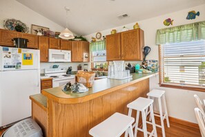 Una cocina con armarios de madera, un microondas, una estufa y una isla grande con taburetes.