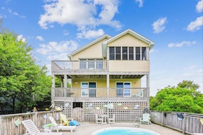 A two-story building with a balcony, a pool, and outdoor seating.