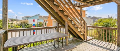 A wooden deck with a bench and a staircase leading to an upper level.