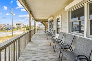Een overdekt terras met houten leuningen en een rij stoelen.