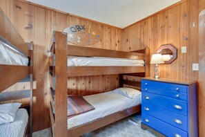 Ein Etagenbett mit Holzkopfstück, eine blaue Kommode mit Schubladen und eine Wanduhr.