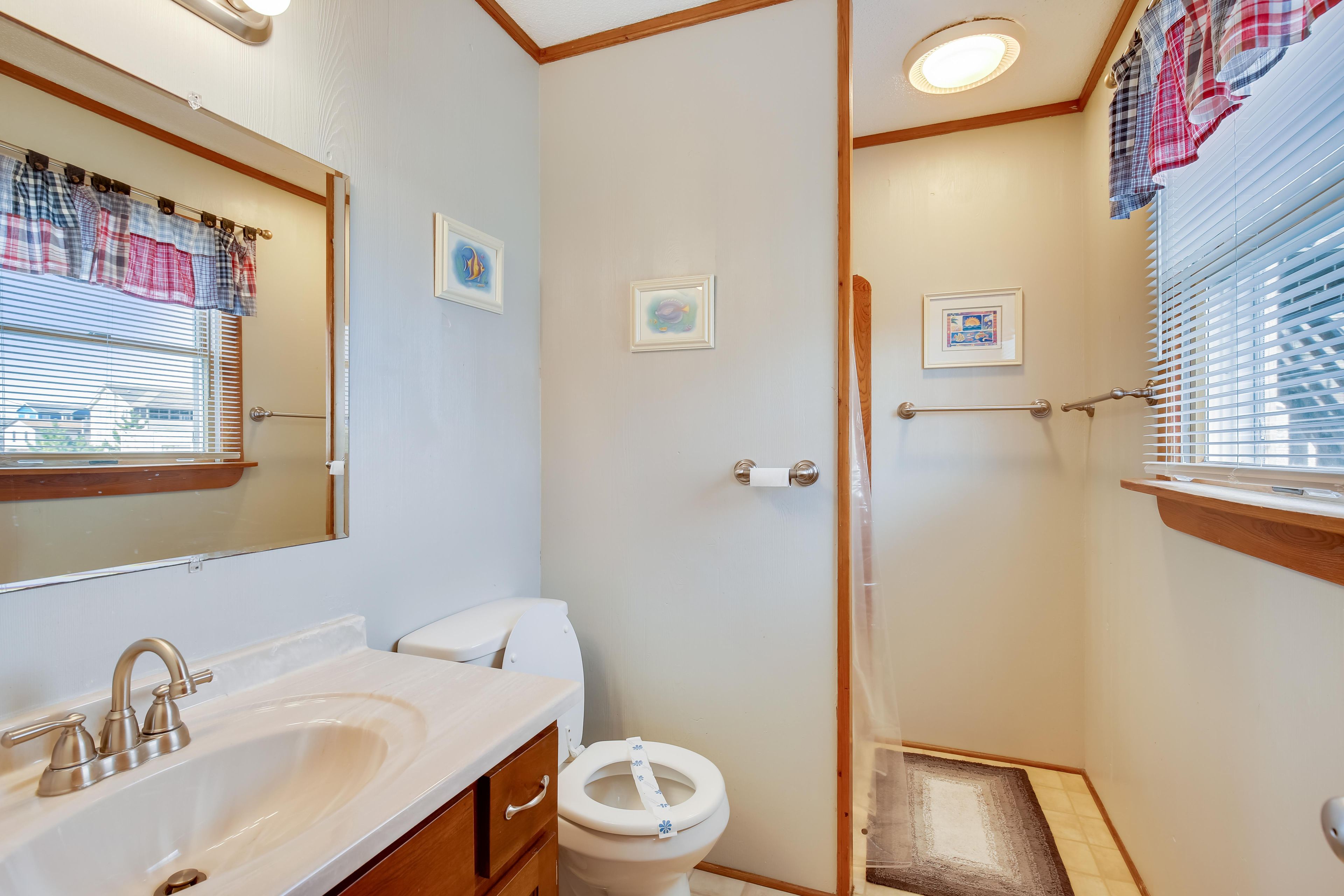 A compact bathroom with a sink, toilet, and shower area.