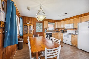 A kitchen with wooden cabinets, a dining table, and white appliances.