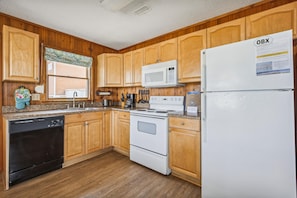 A kitchen with wooden cabinets, a microwave, a refrigerator, and a dishwasher.