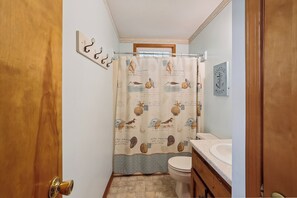 A bathroom with a shower curtain featuring sea creatures, a wooden door, a toilet, and a sink with a countertop. - Sunseeker -- Beat the traffic with a Friday arrival/3 BR Cottage in Kitty Hawk (Kitty Hawk)