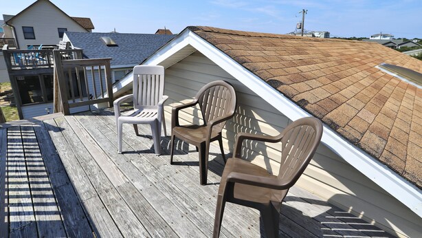 A rooftop deck with two chairs and a wooden railing. - Sunseeker -- Beat the traffic with a Friday arrival/3 BR Cottage in Kitty Hawk (Kitty Hawk)