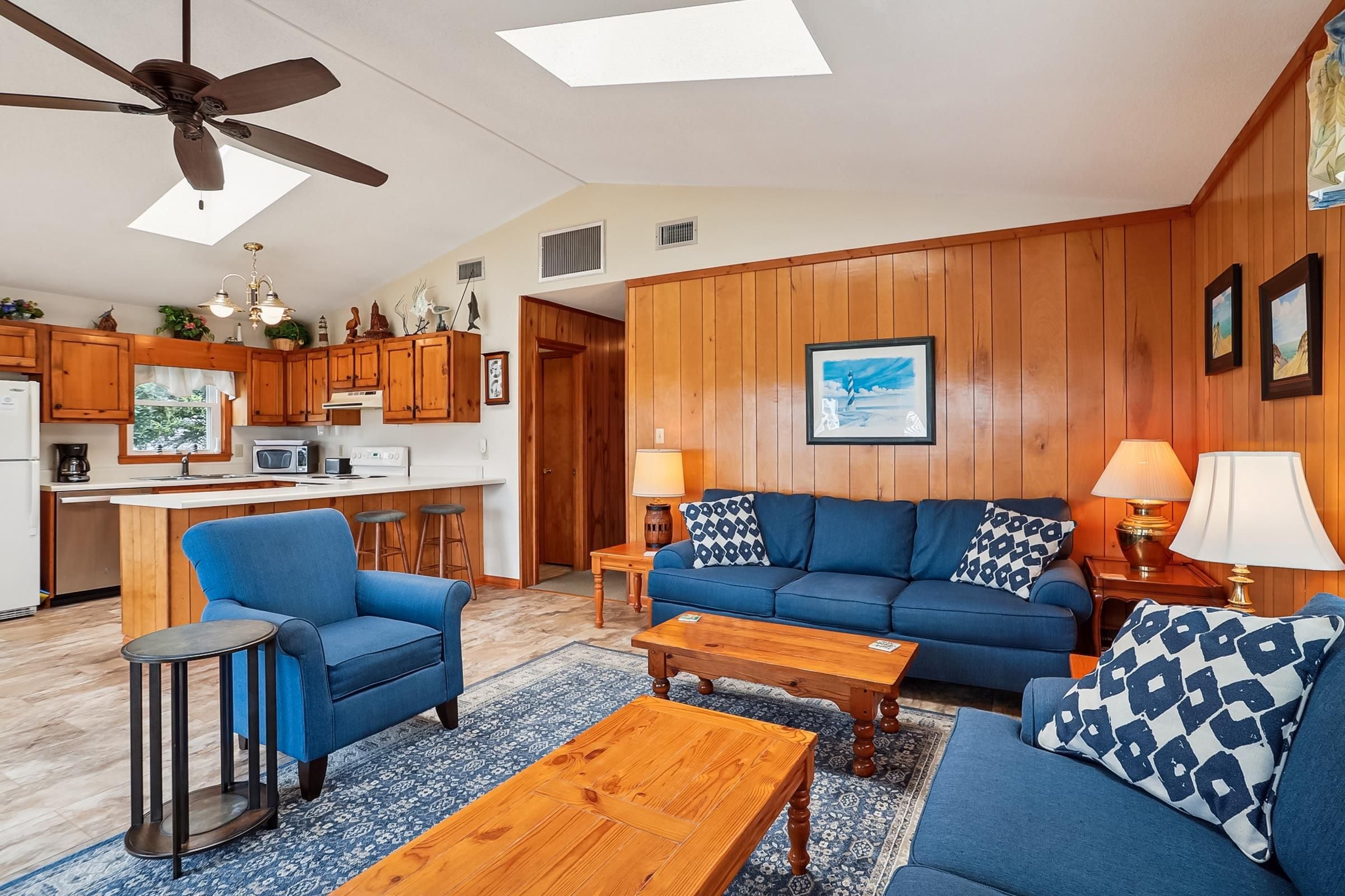 A modern living room with a blue sofa set, a wooden coffee table, and a ceiling fan.