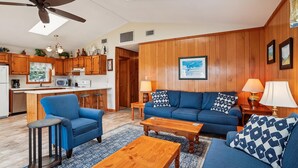 A modern living room with a blue sofa set, a wooden coffee table, and a ceiling fan. - Sunseeker -- Beat the traffic with a Friday arrival/3 BR Cottage in Kitty Hawk (Kitty Hawk)