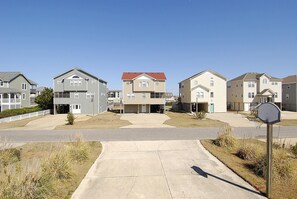 A residential street with houses, a clear sky, and a basketball hoop.