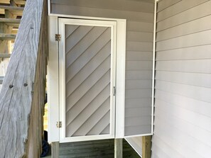 A white door with a diagonal pattern, a wooden deck, and a house with siding. - School Bored --Affordable Cottage just 2 blocks to the ocean (Kill Devil Hills)