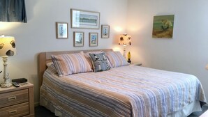 Un dormitorio ordenado con cama, mesitas de noche y lámparas de pared.