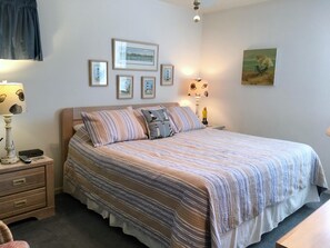 A neatly arranged bedroom with a bed, bedside tables, and wall-mounted lamps.