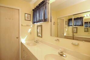 A bathroom with two sinks, a large mirror, and a door with a handle.