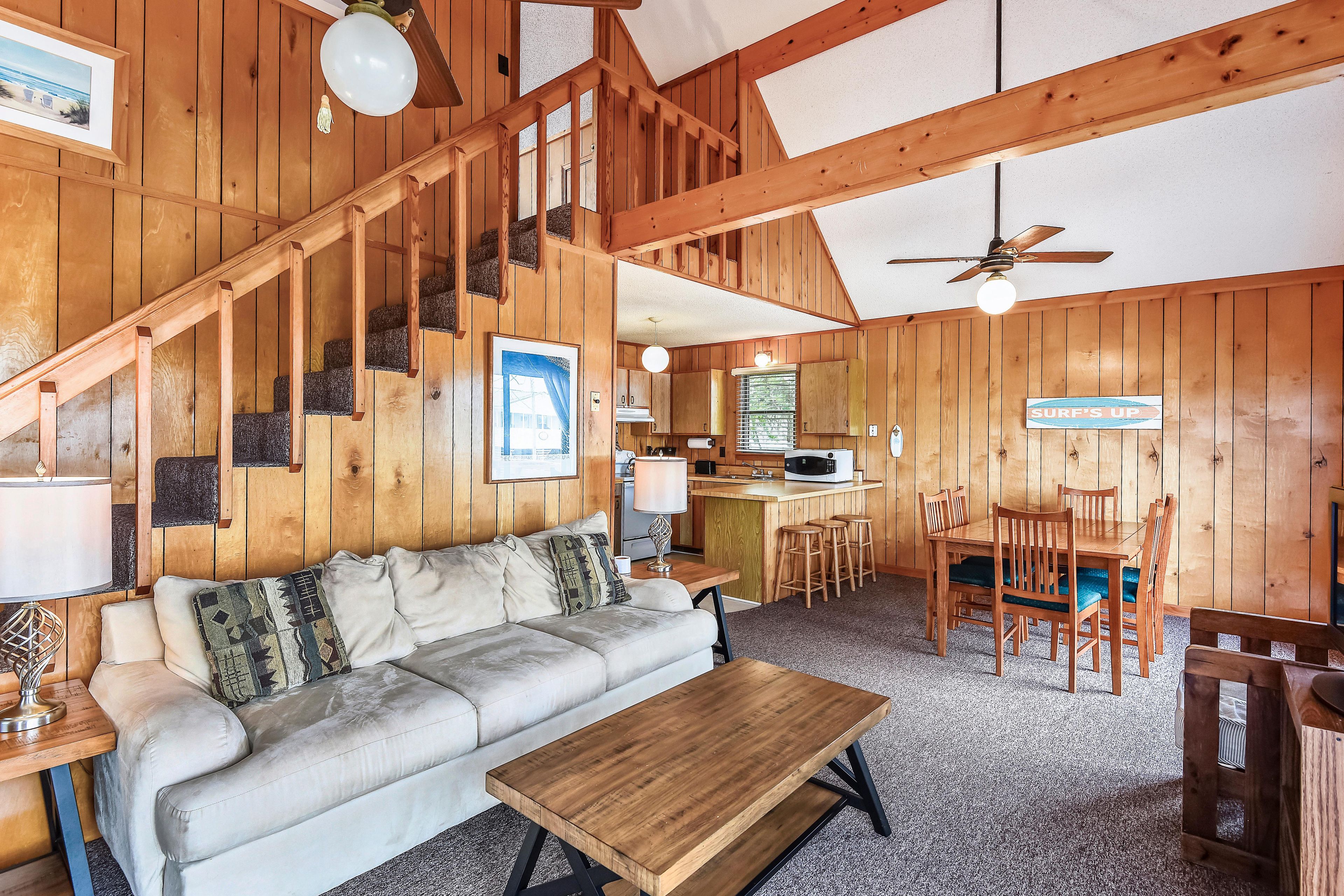 A wooden interior with a sofa, a dining table, and a kitchen area.