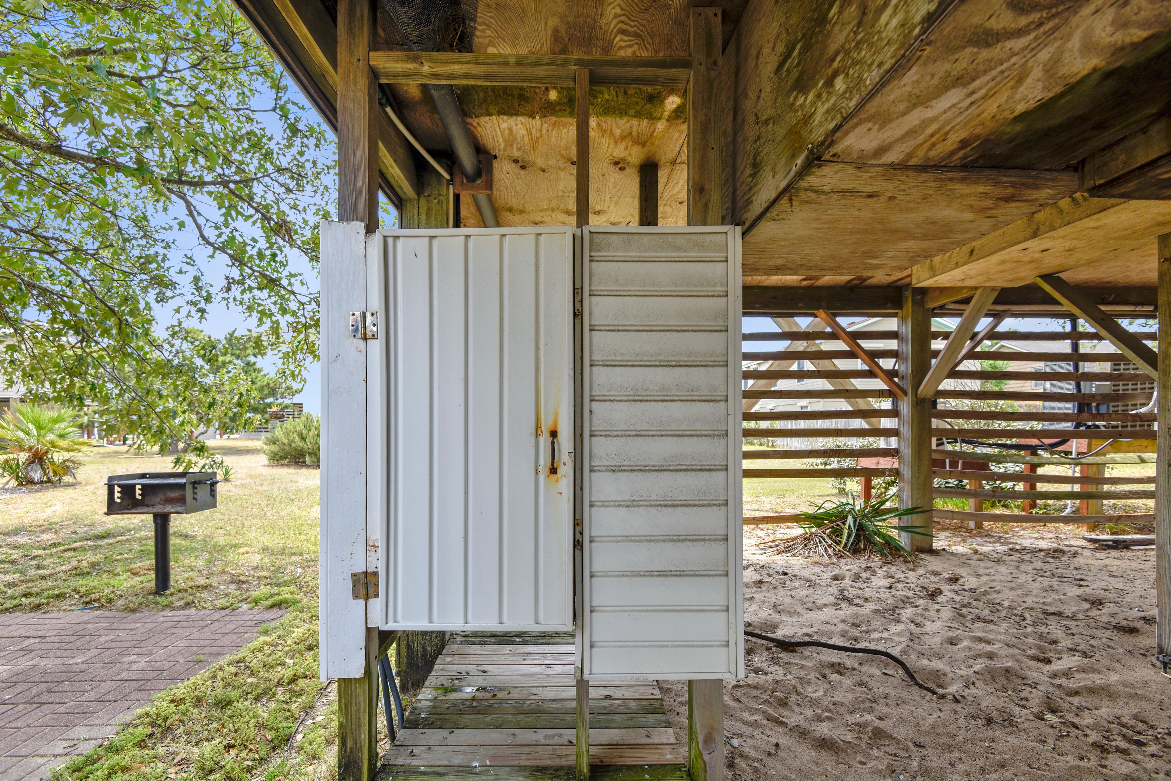 Une boîte de couleur blanche, de type coffret de raccordement, dotée d’un loquet métallique et fixée à une structure en bois recouverte d’un toit en métal.