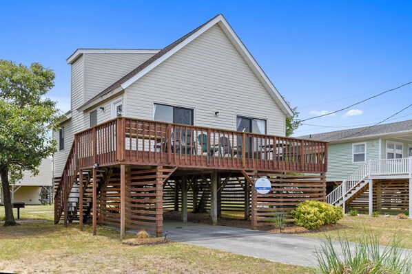A two-story house with a wooden deck and a covered porch.