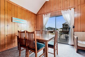 A wooden interior with a dining table, chairs, and a sign that reads 'SURF'S UP'.