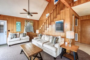 A cozy living room with a wooden interior, two sofas, a coffee table, and a ceiling fan.