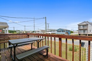 A wooden deck with picnic tables, a view of a residential area with houses, and power lines overhead.