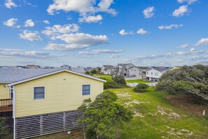A residential area with houses, a grassy yard, and a clear sky. - Gone to Carolina -- Recently Remodeled Home with Pool, Hot Tub, & Putting Green (Kitty Hawk)