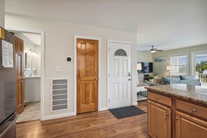 A kitchen with wooden cabinets, a refrigerator, and a dining area with a table and chairs. - Gone to Carolina -- Recently Remodeled Home with Pool, Hot Tub, & Putting Green (Kitty Hawk)