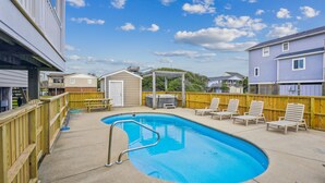 A residential backyard with a swimming pool, wooden deck, and lounge chairs. - Gone to Carolina -- Recently Remodeled Home with Pool, Hot Tub, & Putting Green (Kitty Hawk)