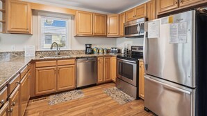 A modern kitchen with wooden cabinets, stainless steel appliances, and a granite countertop.