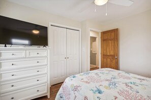 Une chambre à coucher avec un lit, une commode, un téléviseur et une armoire.