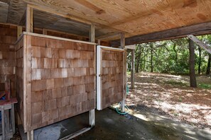 A wooden structure with a partially open door, a concrete floor, and a hose visible outside.