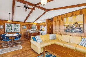 L’intérieur d’un chalet accueillant, avec un coin repas en bois, un canapé et une cuisine.