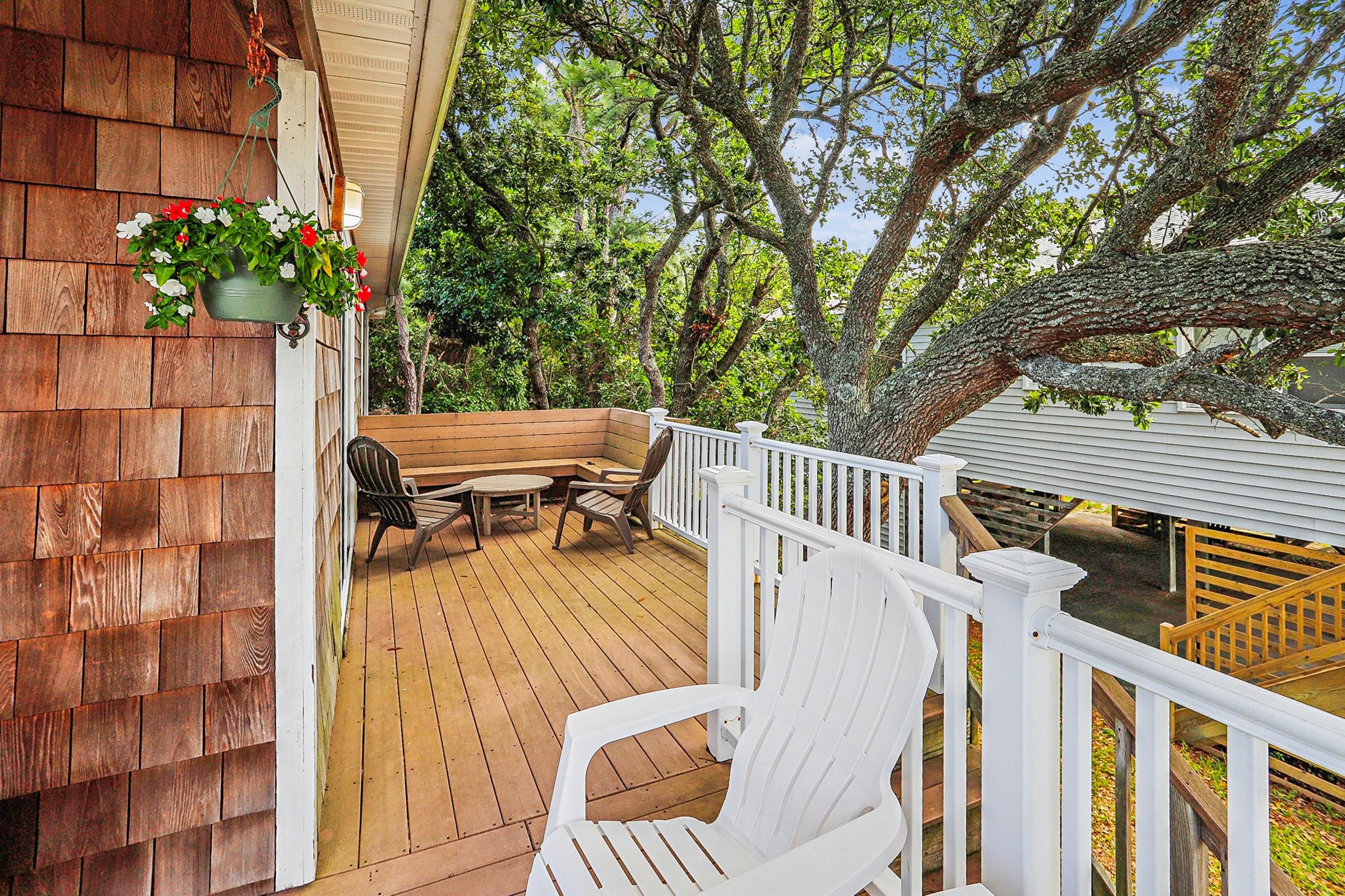 A wooden deck with outdoor furniture, a white railing, and a hanging flower pot.