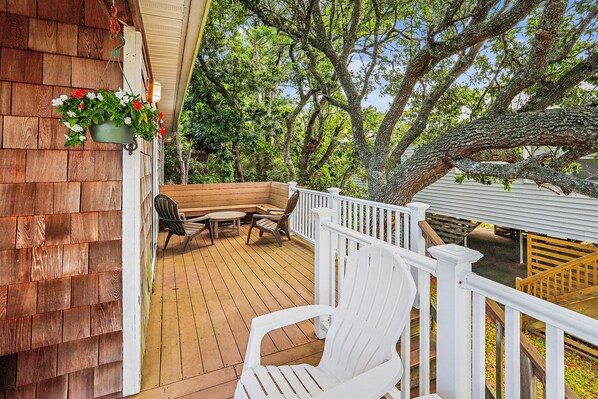 A wooden deck with outdoor furniture, a white railing, and a hanging flower pot.