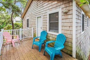 Une terrasse en bois avec deux chaises et une rambarde blanche.