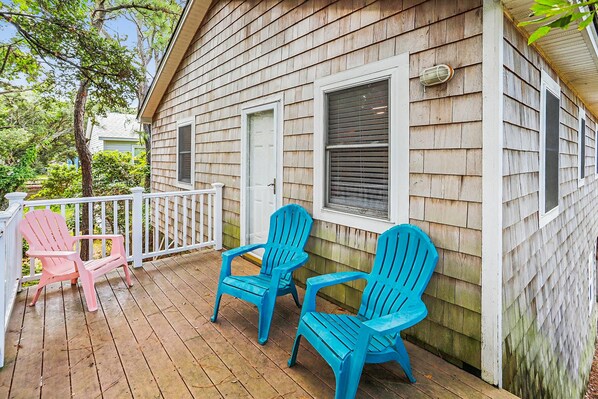 Une terrasse en bois avec deux chaises et une rambarde blanche.