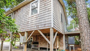 Een houten huis met twee verdiepingen, een balkon, een garage en een keurkast.