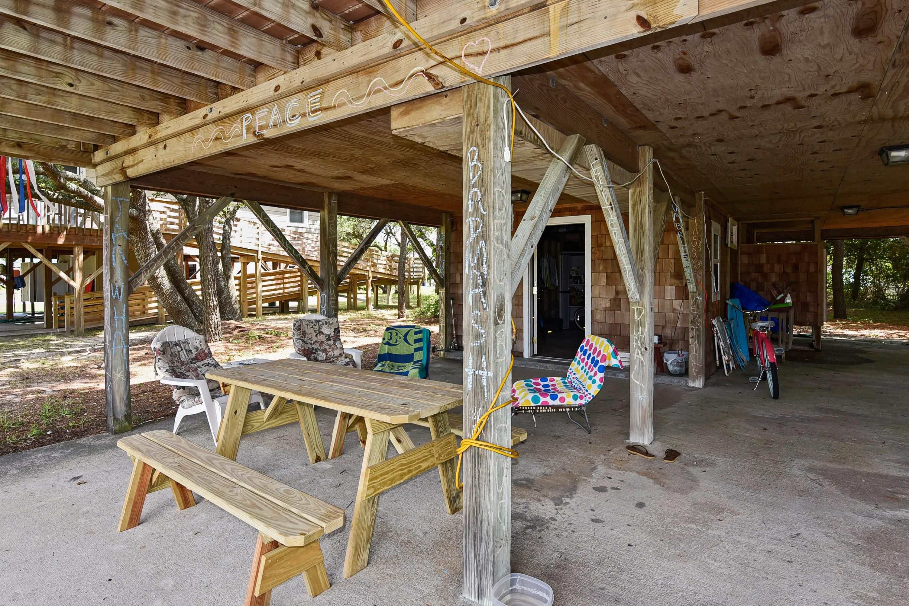 An outdoor wooden structure with a covered seating area, including benches and a table.