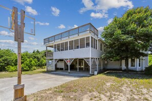 Un edificio de dos pisos con un balcón, una canasta de baloncesto y un área techada con un letrero.
