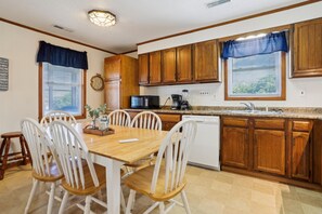 Una cocina con armarios de madera, una mesa de comedor con sillas, un microondas y una cafetera.