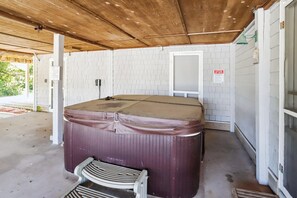 A spa room with a hot tub, a bench, and a tiled wall with a caution sign. - Doris's Day-- 4BR Oceanside home in Duck with Private Hot Tub (Duck)