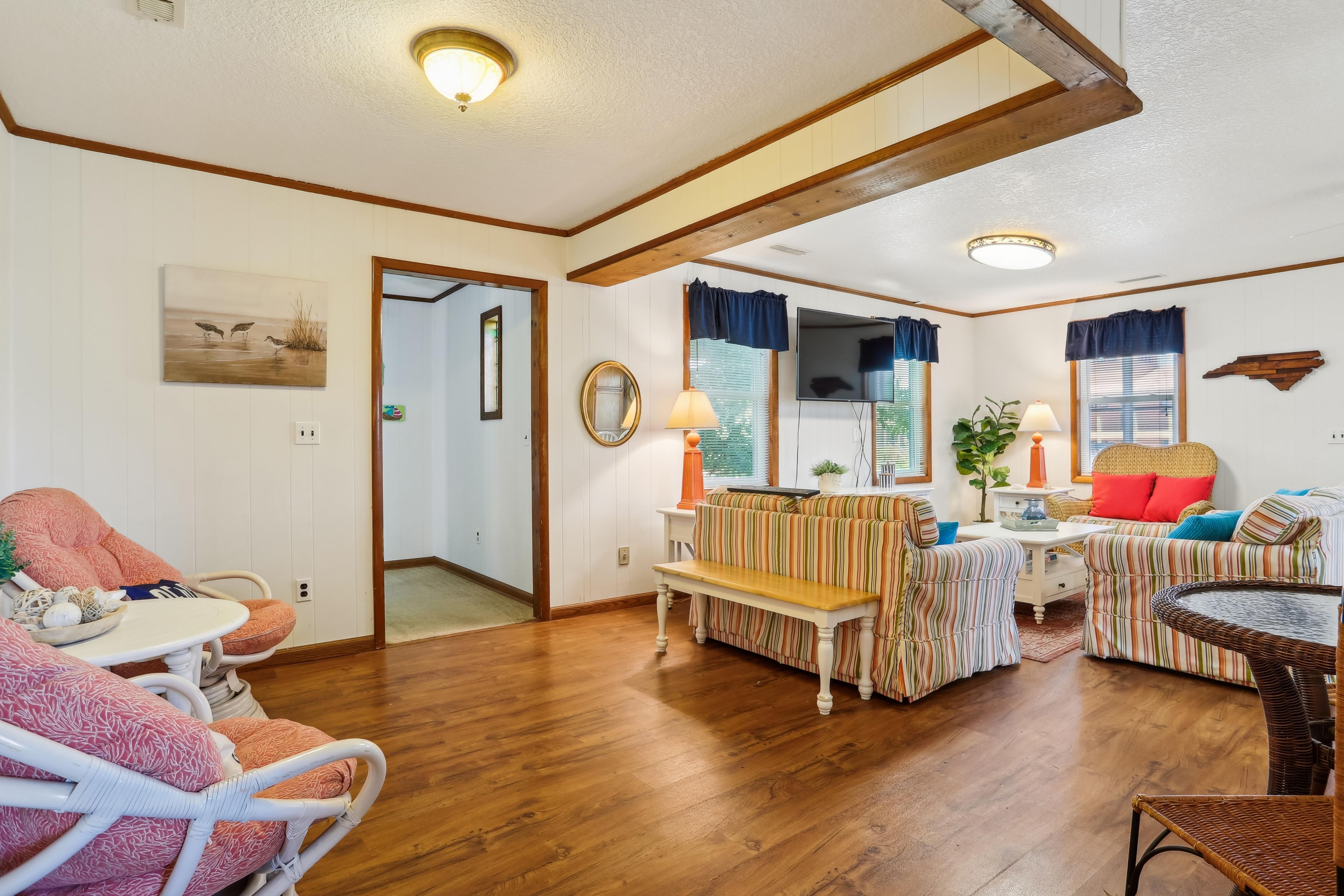A spacious room with a wooden floor, a sofa set, a dining table, and a television.