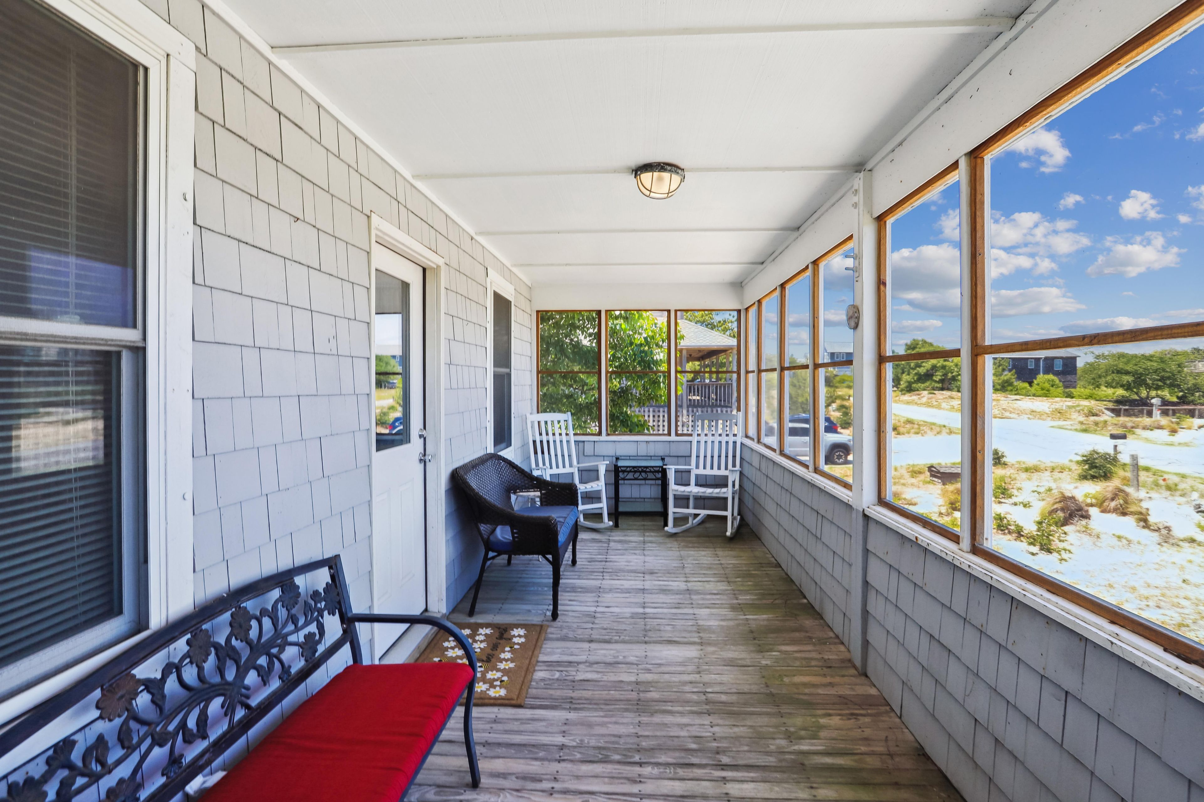 En overdækket veranda med et bord, stole, en bænk og udsigt til landskabet.