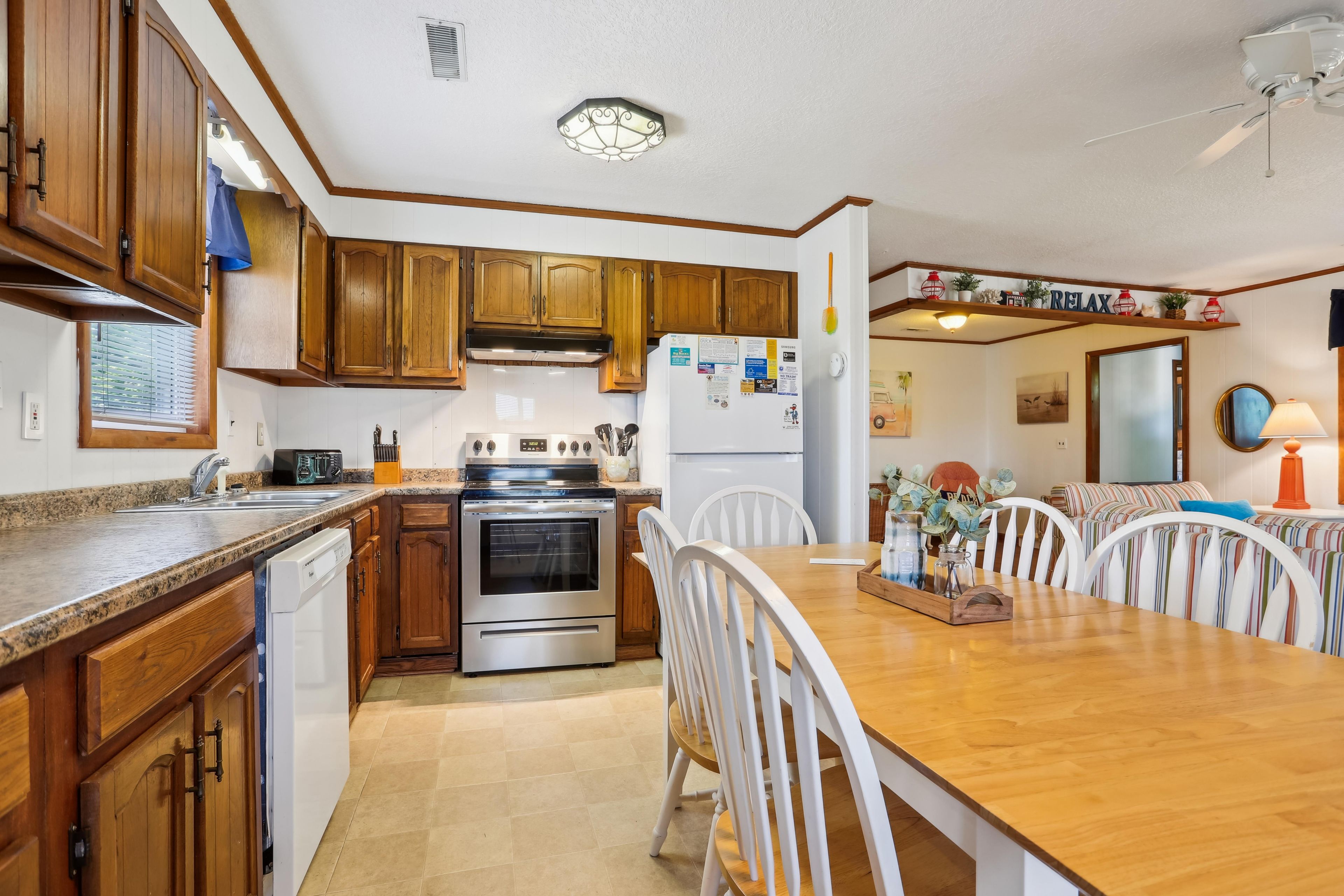 A kitchen with wooden cabinets, a stainless steel stove, and a dining table with chairs.