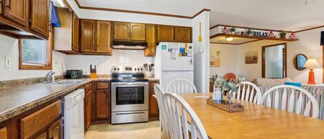 A kitchen with wooden cabinets, a stainless steel stove, and a dining table with chairs.