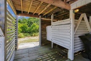 Una estructura de madera con techo inclinado, terraza de madera y vista a la vegetación.